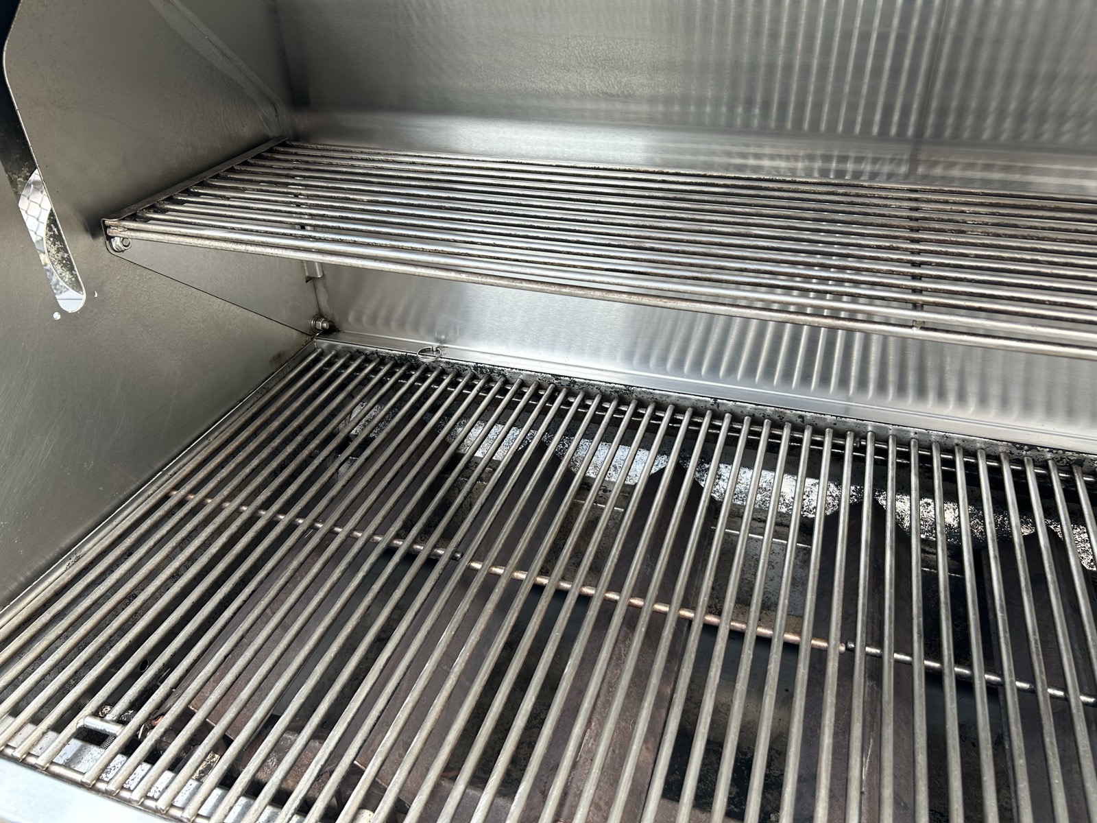 Same BBQ interior after deep clean — grates and warming rack restored